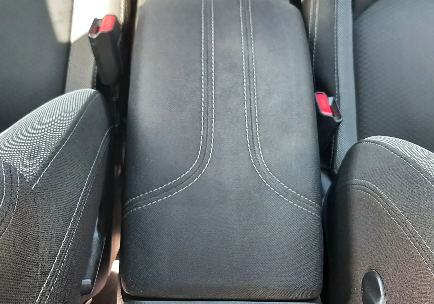 Vue plongeante sur l'accoudoir central en tissu gris noir du Nissan Qashqai 2018, entouré des sièges avant.