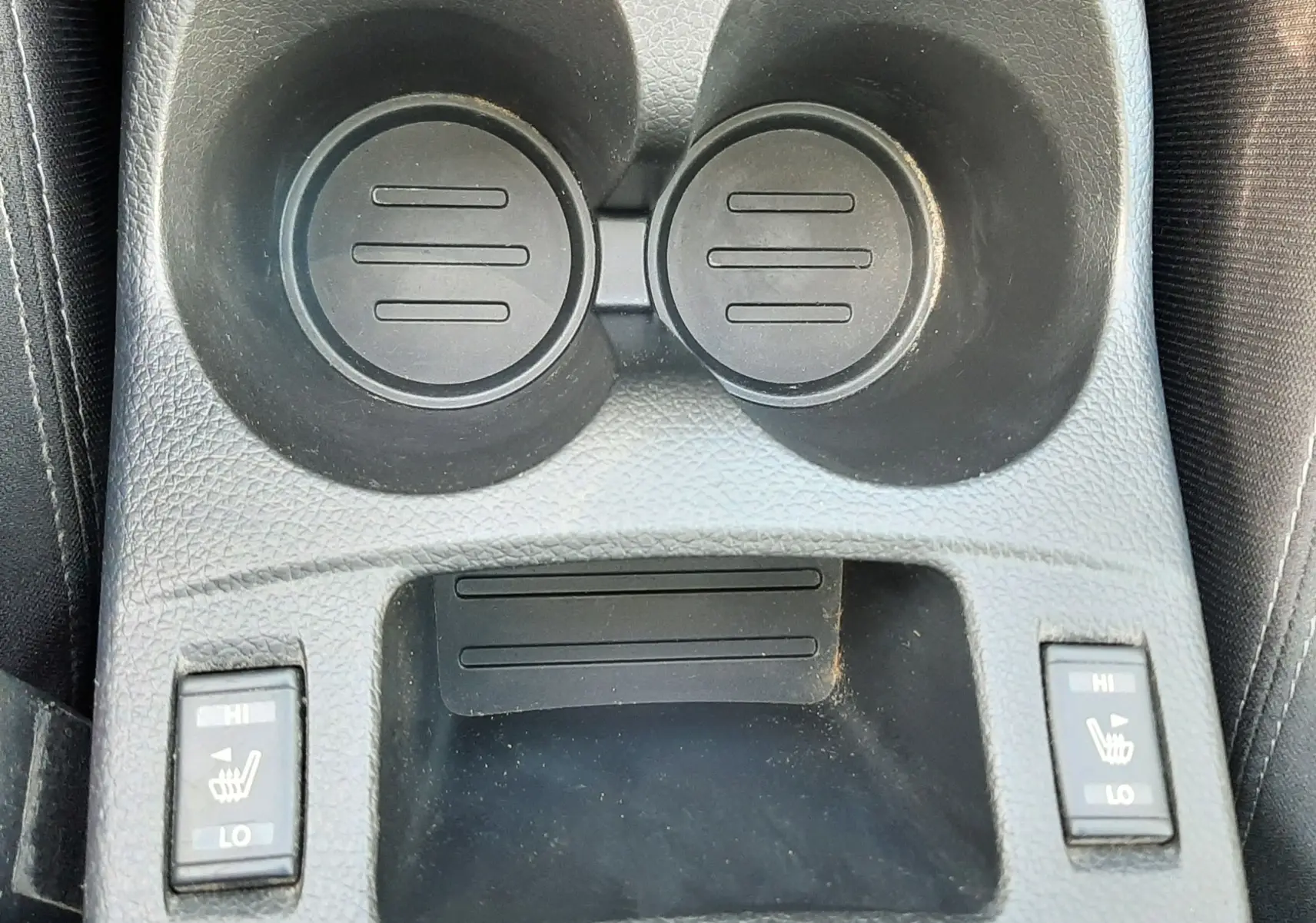 Gros plan sur la console centrale noire du Nissan Qashqai 2018 avec porte-gobelets et commandes de sièges chauffants.