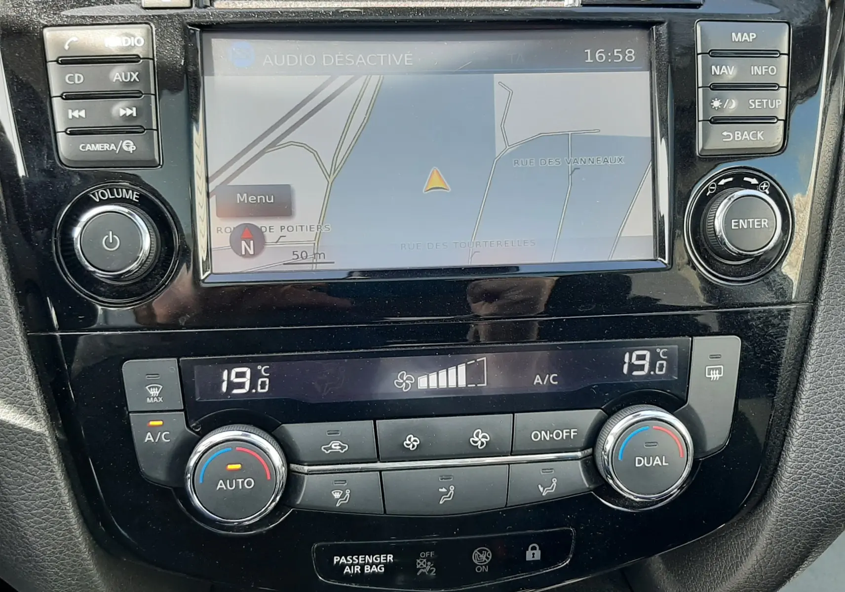 Vue rapprochée de la console centrale du Nissan Qashqai 2018, écran GPS et commandes climatisation digitales visibles.