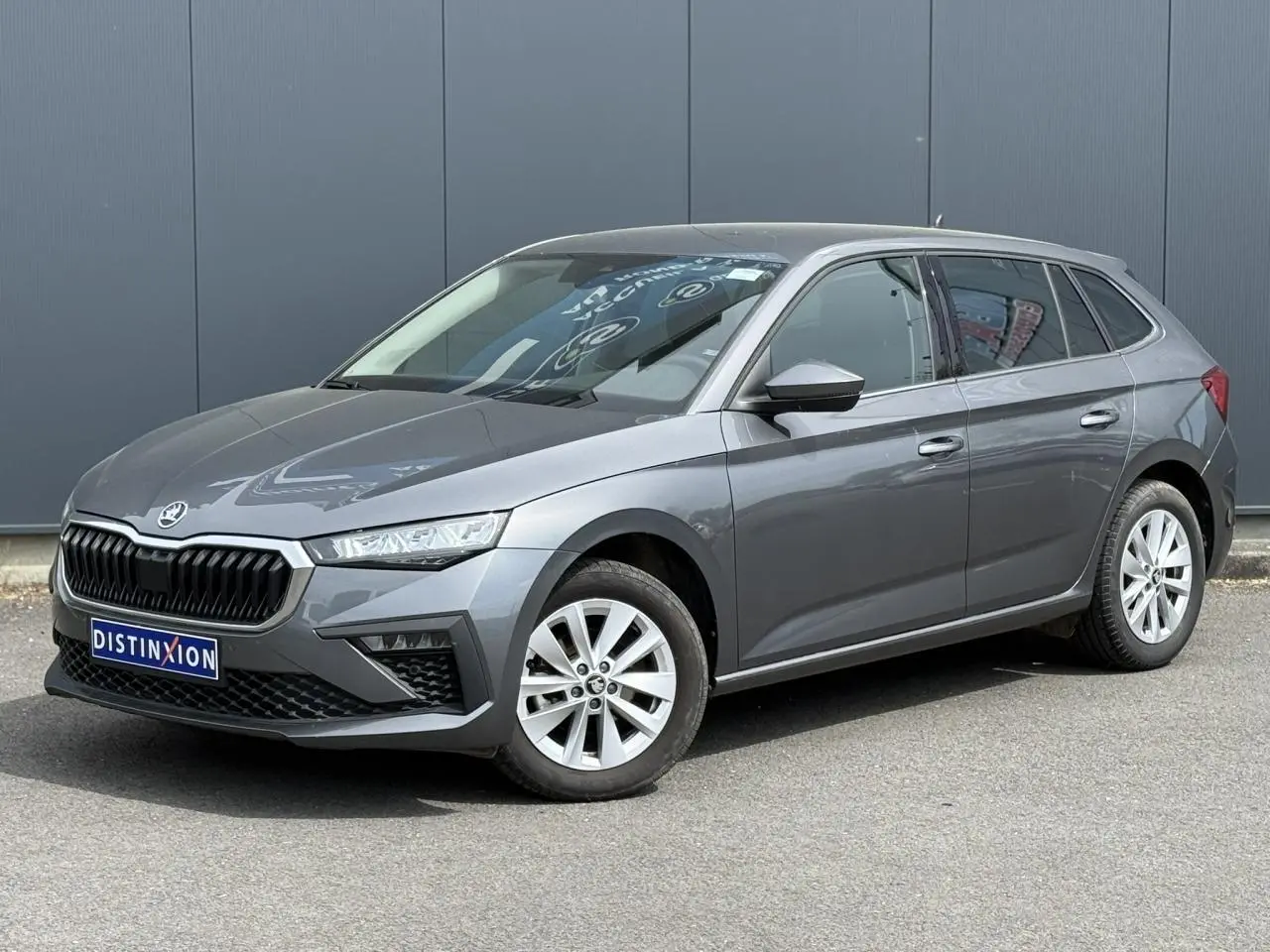 Skoda Scala TSI 116 gris graphite en 3/4 avant droit, avec jantes alliage et calandre noire distinctive.