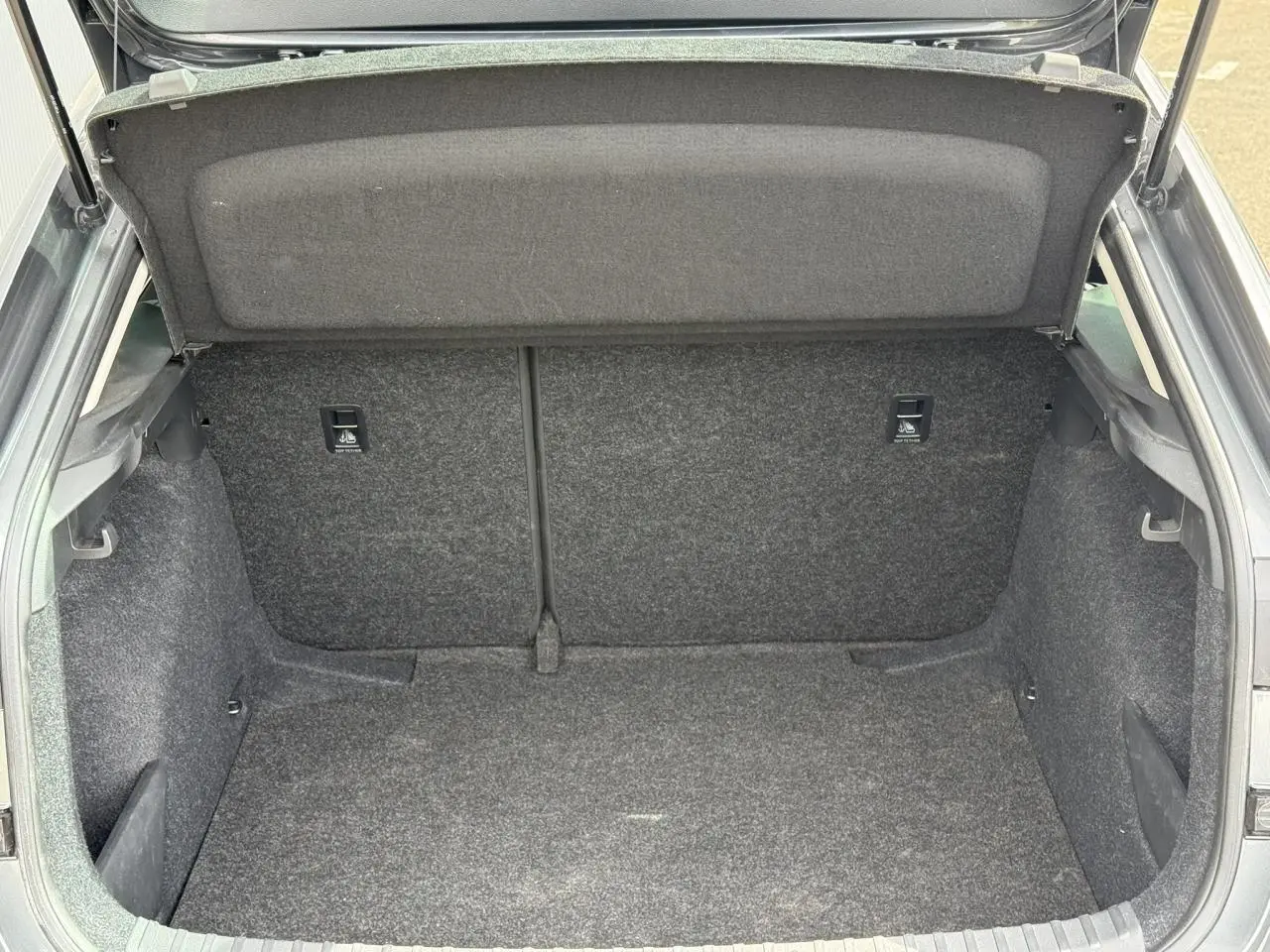 Coffre ouvert vu de l'arrière d'une Skoda Scala gris graphite, montrant l'espace de rangement intérieur.