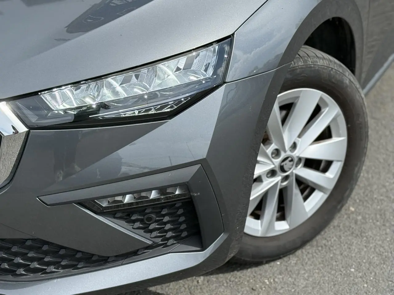 Gros plan sur l'avant droit gris graphite d'une Skoda Scala TSI 116 avec phares LED et jante alliage 16 pouces.