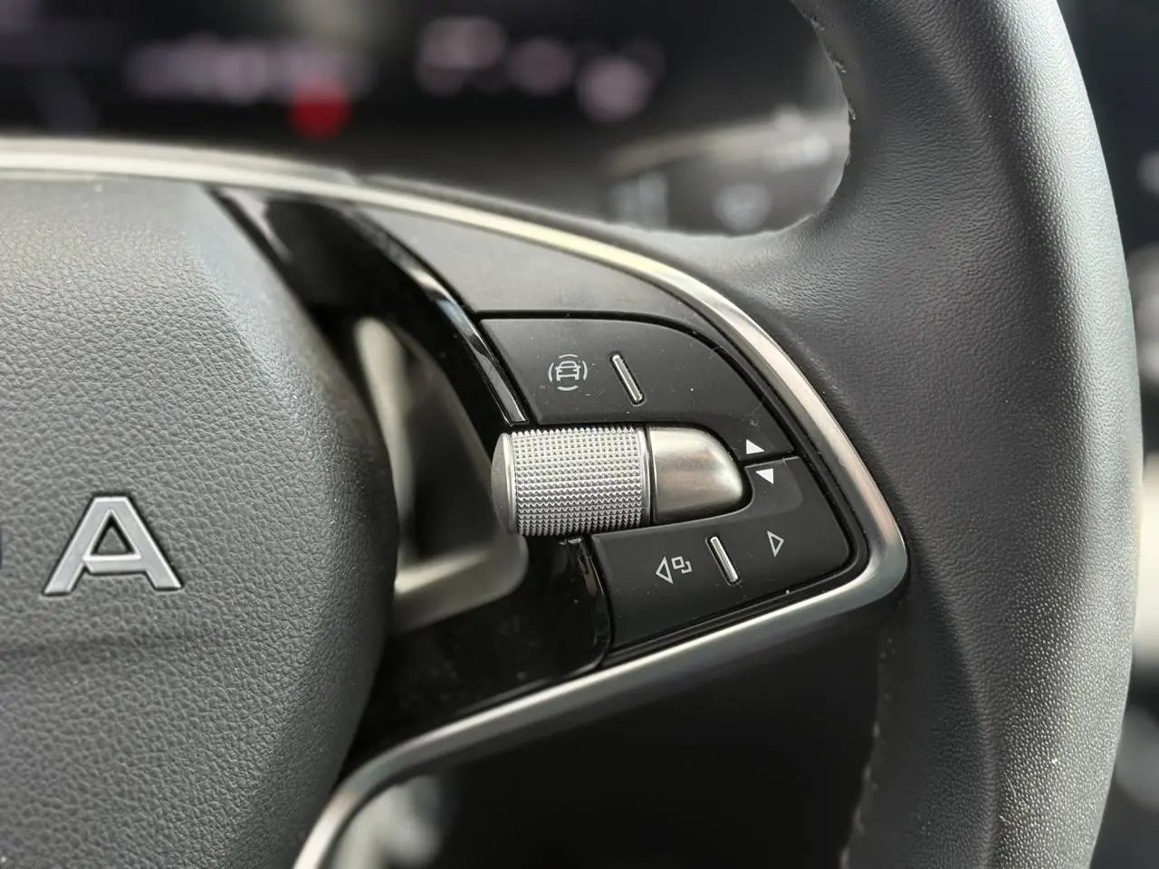 Gros plan sur les commandes à droite du volant en cuir noir du Skoda Scala TSI 116 gris graphite, année 2025.
