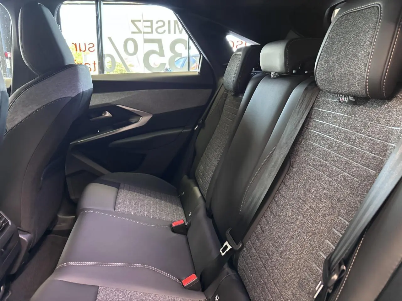 Vue intérieure côté droit des sièges arrière gris tissu et cuir du Peugeot 3008 hybride blanc 2026 avec ceintures de sécurité.