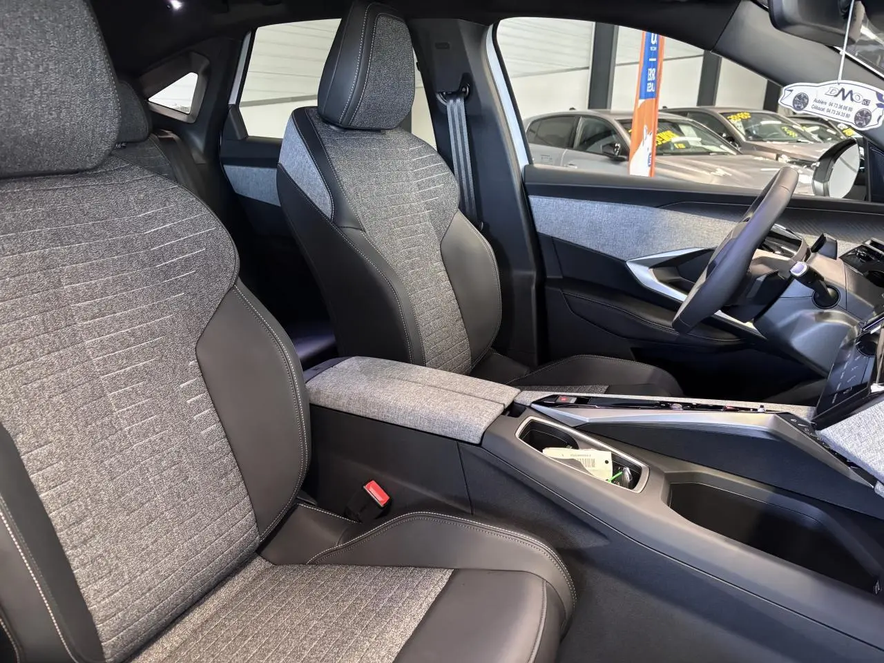 Vue intérieure côté droit du Peugeot 3008 2026, montrant les sièges tissu gris et cuir noir avec console centrale assortie.