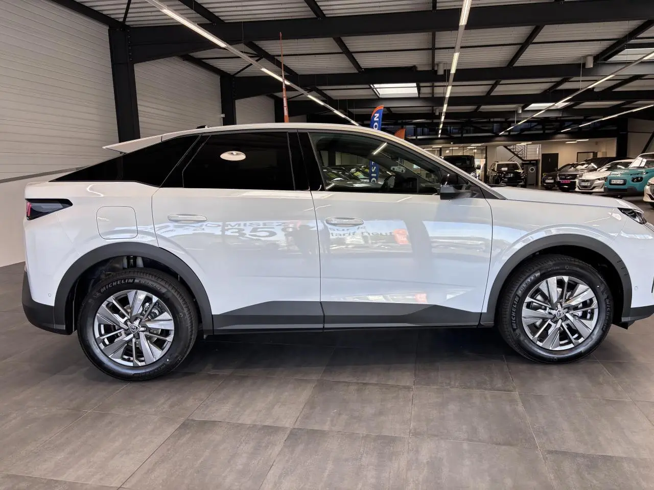 Profil droit d’un Peugeot 3008 blanc hybride 2026 en showroom avec jantes alliage 18 pouces et vitres teintées.