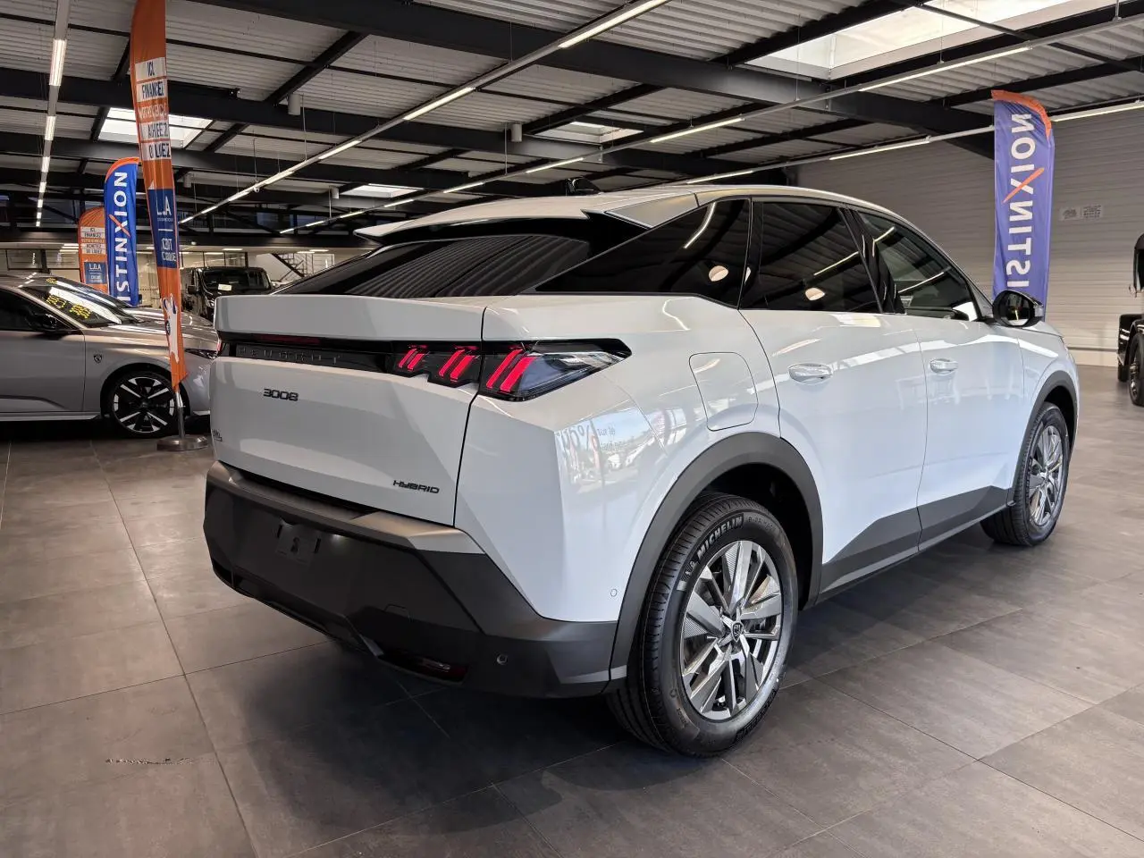 Vue 3/4 arrière droite du Peugeot 3008 hybride blanc avec feux arrière à LED 3 griffes et jantes alliage 18 pouces Basel.
