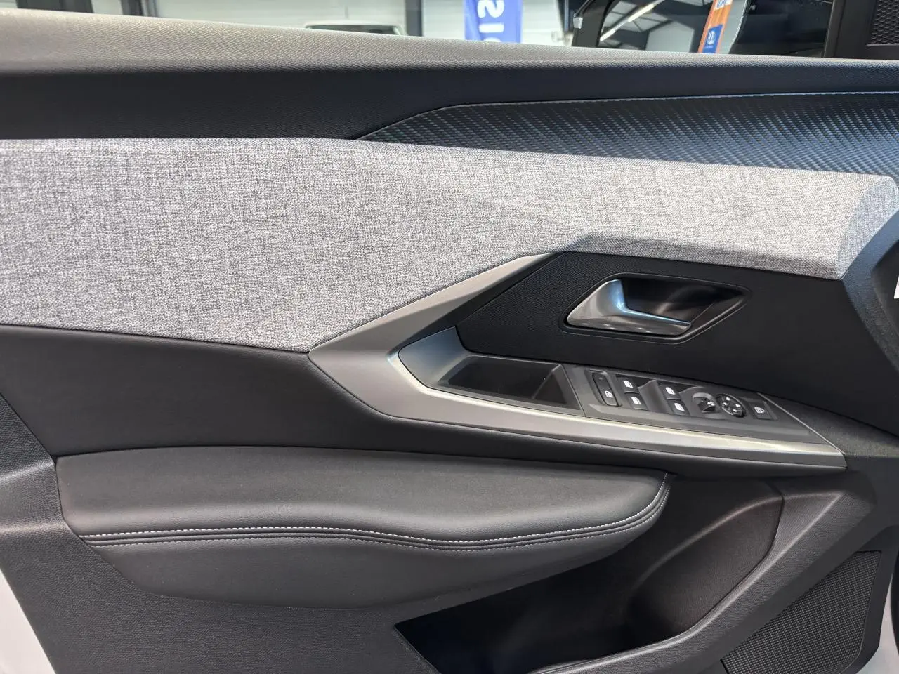 Détail de la porte avant gauche du Peugeot 3008 blanc, avec garniture tissu gris et commandes électriques.