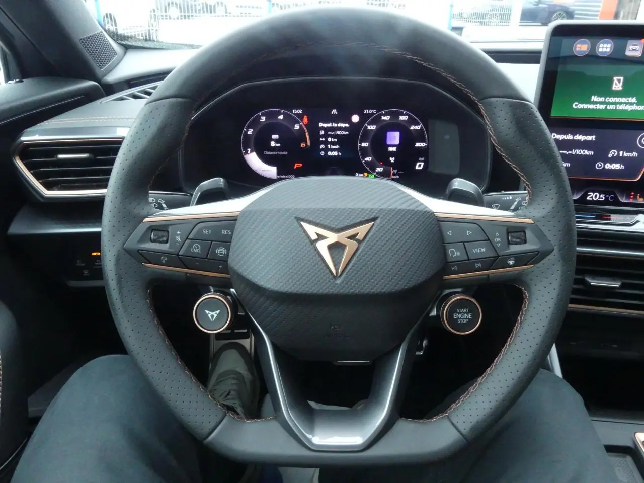 Vue rapprochée du volant perforé noir avec logo CUPRA cuivré et tableau de bord digital du CUPRA Formentor gris Graphène 2025.