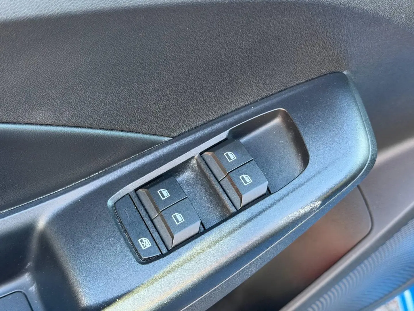 Gros plan sur les commandes des vitres électriques côté conducteur de la MG3 1.5 Hybrid+ 2024 en Como Blue métallisé.
