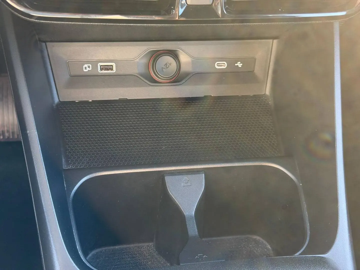 Gros plan sur la console centrale noire du MG3 1.5 Hybrid+ 2024 avec prise 12V, USB et rangement intégré.