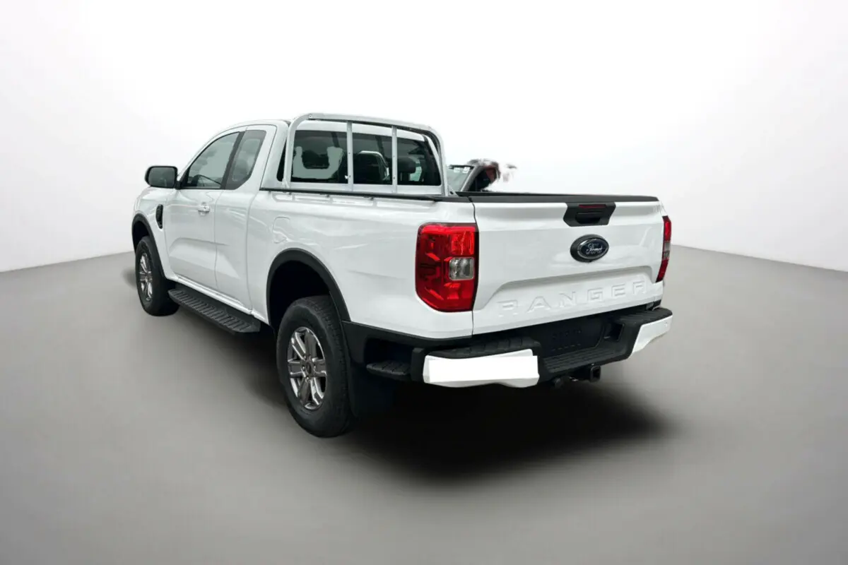 Vue 3/4 arrière gauche du Ford Ranger blanc glacier 2026 avec benne et marchepieds latéraux visibles.