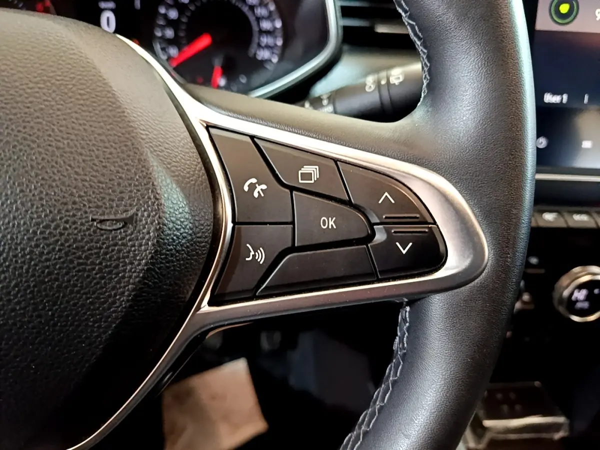 Gros plan sur le volant cuir synthétique noir de la Renault Clio Business TCe 100, avec commandes multifonctions visibles.