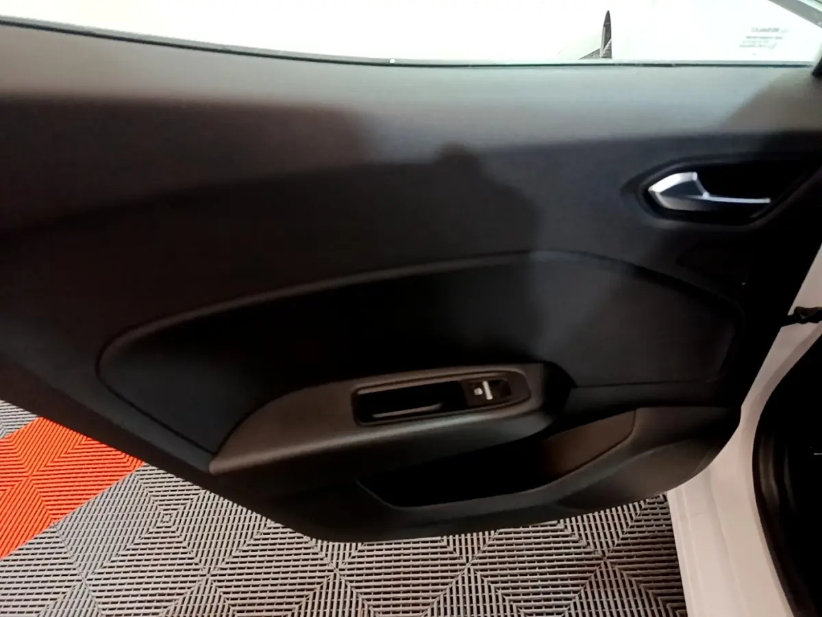 Vue rapprochée de la porte intérieure côté droit de la Renault Clio Business TCe 100 blanche, avec commande de vitre électrique.