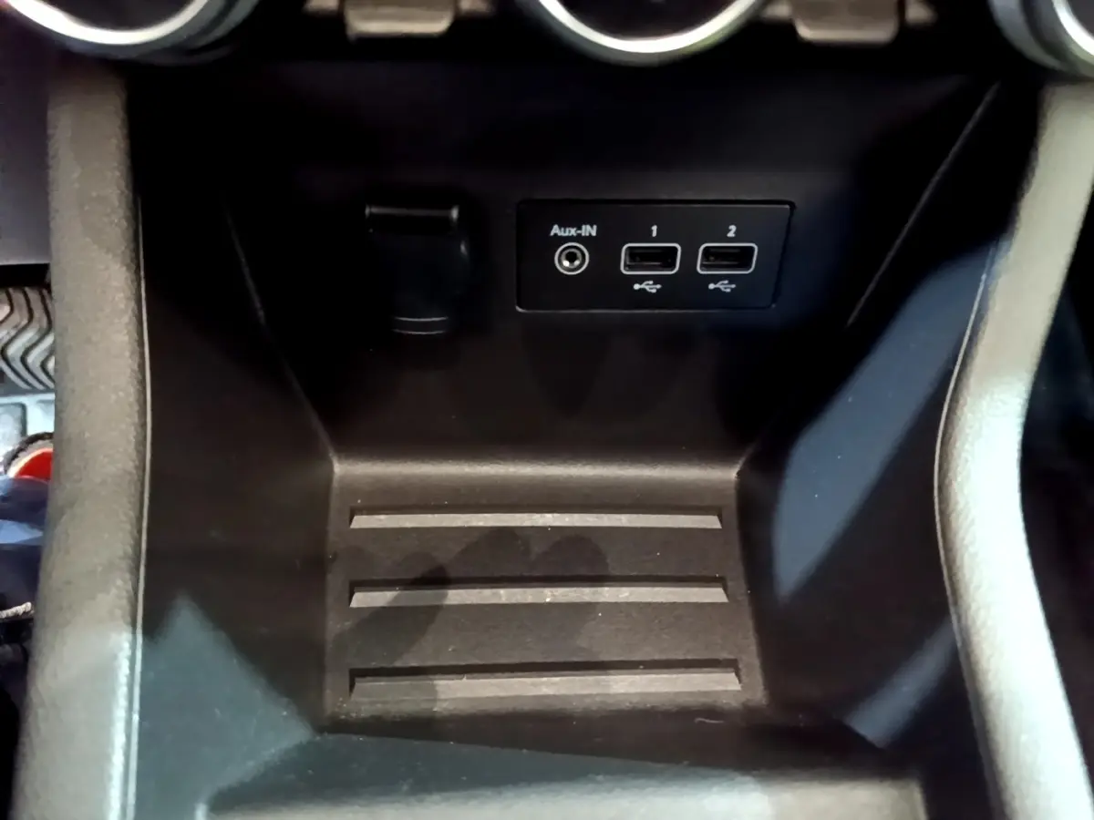 Gros plan sur la console centrale noire de la Renault Clio Business TCe 100 avec ports USB et prise Aux-IN.