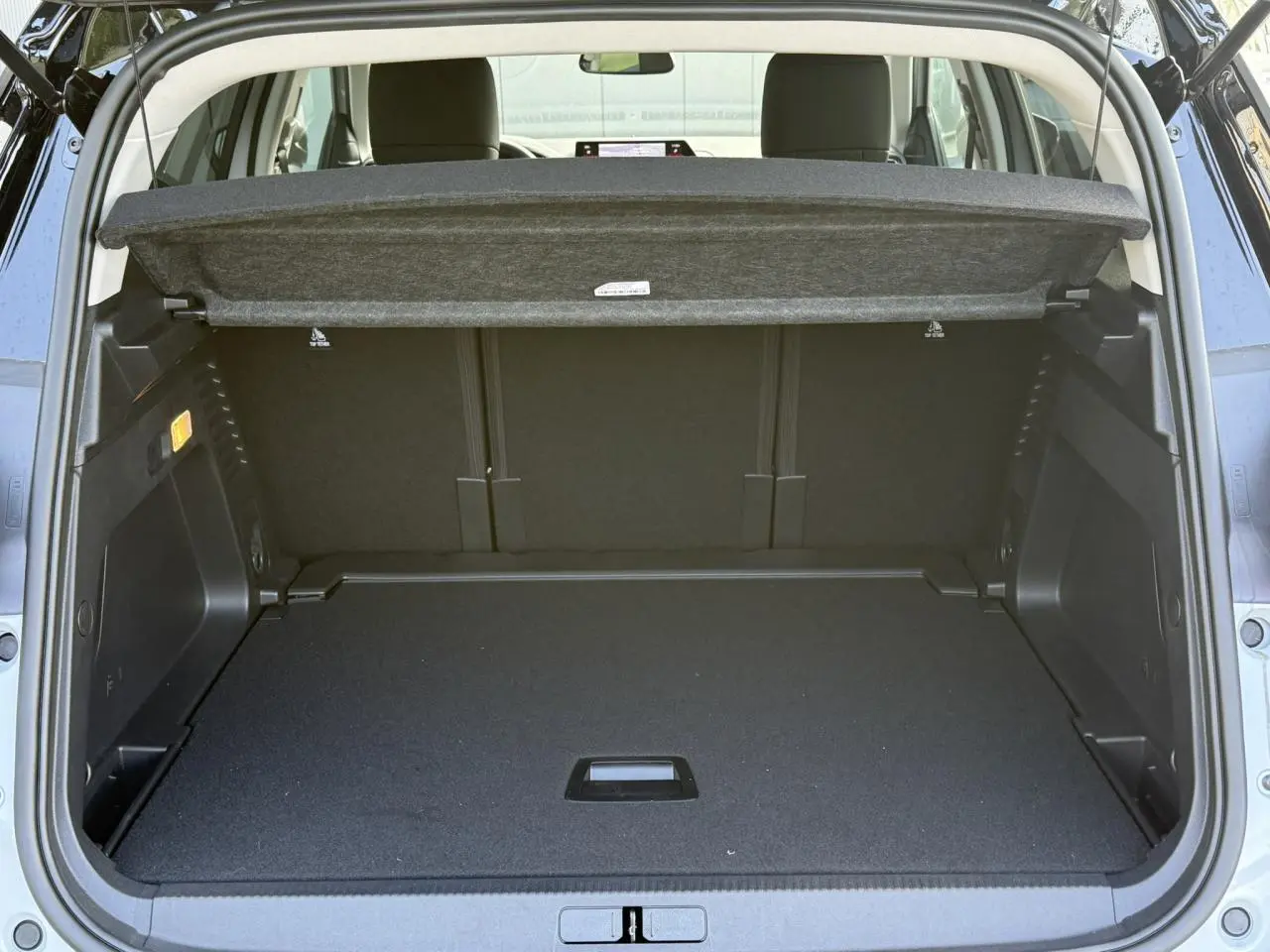 Vue arrière du coffre ouvert du Citroën C5 Aircross blanc Okenite, montrant l'espace de chargement et la tablette cache-bagages.
