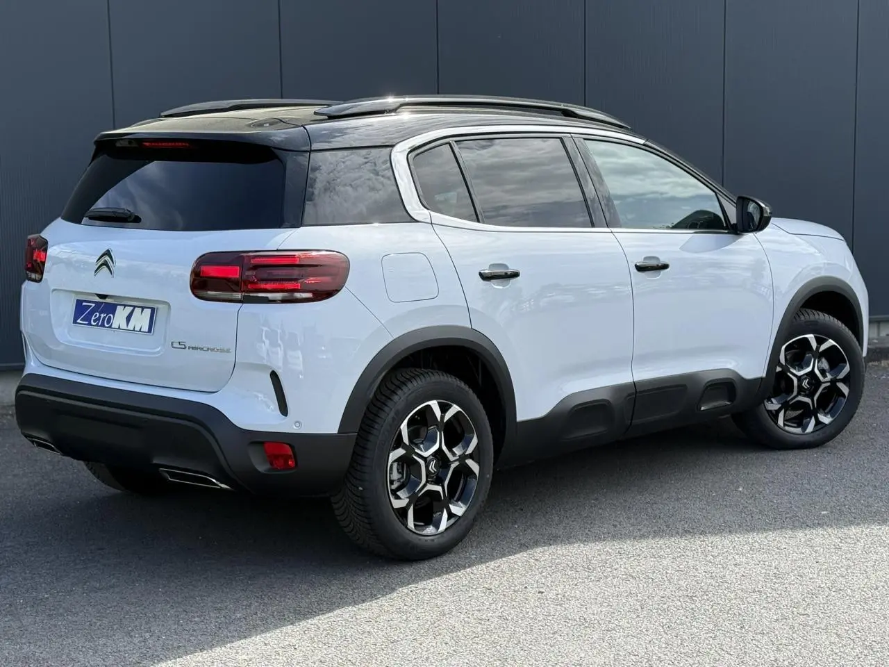 Vue 3/4 arrière droite du Citroën C5 Aircross blanc Okenite avec toit noir Perla Nera et jantes alliage bi-ton.
