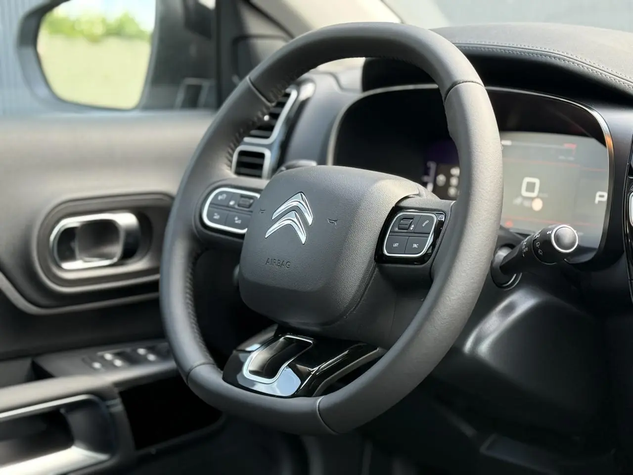 Vue rapprochée du volant cuir noir de la Citroën C5 Aircross 2026 avec commandes intégrées et tableau de bord numérique.
