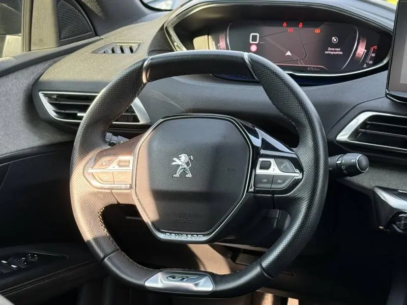 Vue rapprochée du volant cuir GT du Peugeot 3008 2024, avec tableau de bord numérique et commandes intégrées.