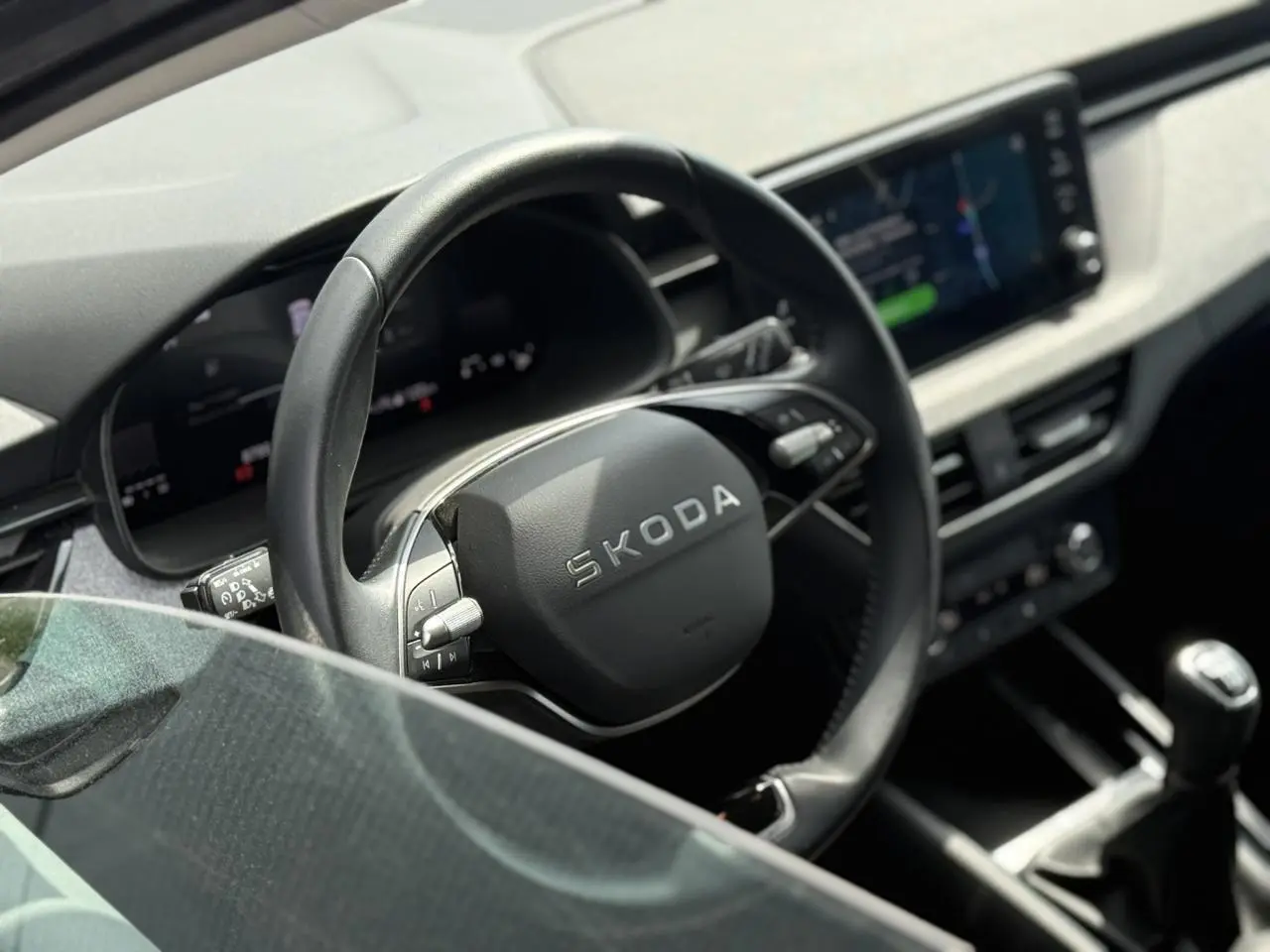 Vue intérieure rapprochée du volant en cuir noir et du tableau de bord digital d’une Skoda Scala TSI 116 Gris Graphite.