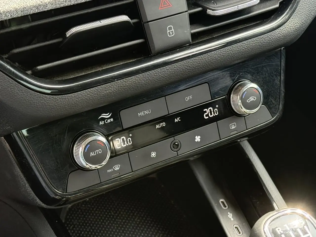 Gros plan sur la console centrale de la Skoda Scala TSI 116 Sélection 2025, montrant la climatisation automatique bi-zone et les commandes en noir brillant.