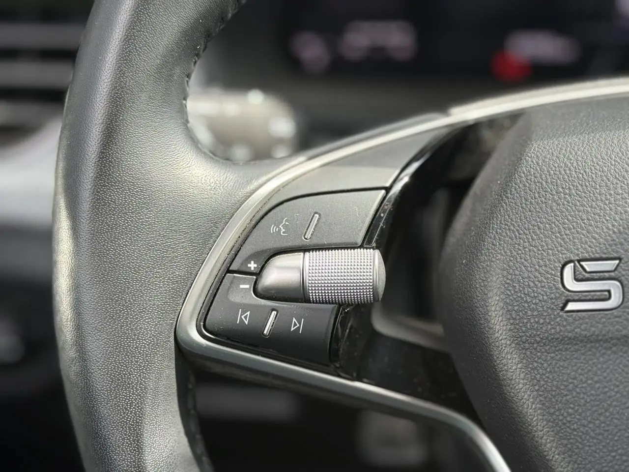 Gros plan sur le volant cuir de la Skoda Scala gris graphite, avec commandes audio intégrées côté gauche.