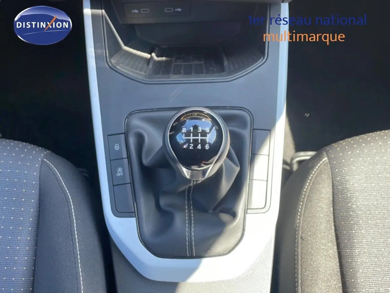 Le levier de vitesse manuel noir du SEAT Arona 2025, vu de dessus entre les sièges gris foncé à motifs.