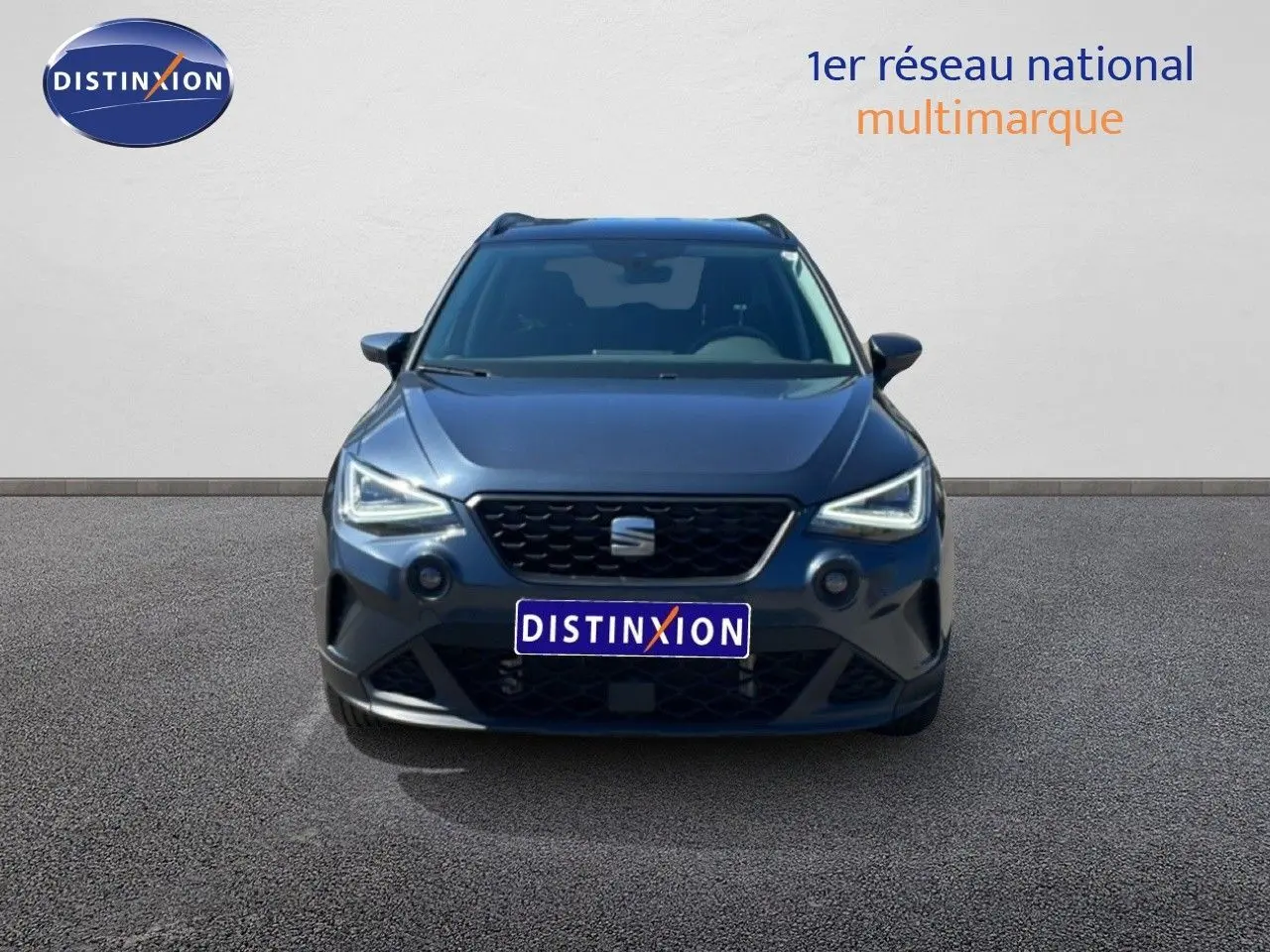 Vue frontale d'un SEAT Arona 2025 gris Magnetic Metal avec toit noir, phares LED allumés sur fond neutre.