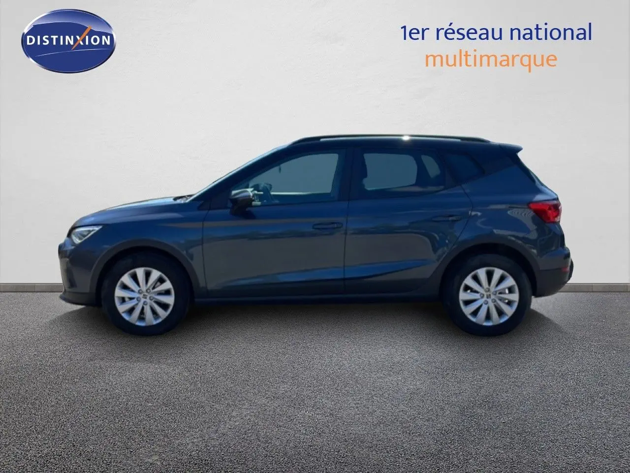 Vue de profil côté gauche d'un SEAT Arona gris Magnetic Metal avec toit noir, en arrière-plan un mur blanc.
