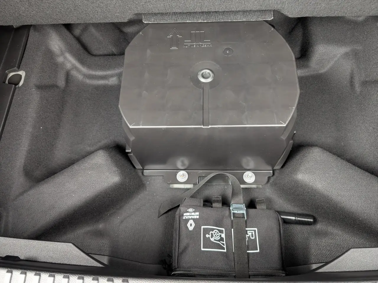Vue rapprochée du coffre du Renault Austral gris, montrant le rangement sous plancher avec trousse à outils attachée.