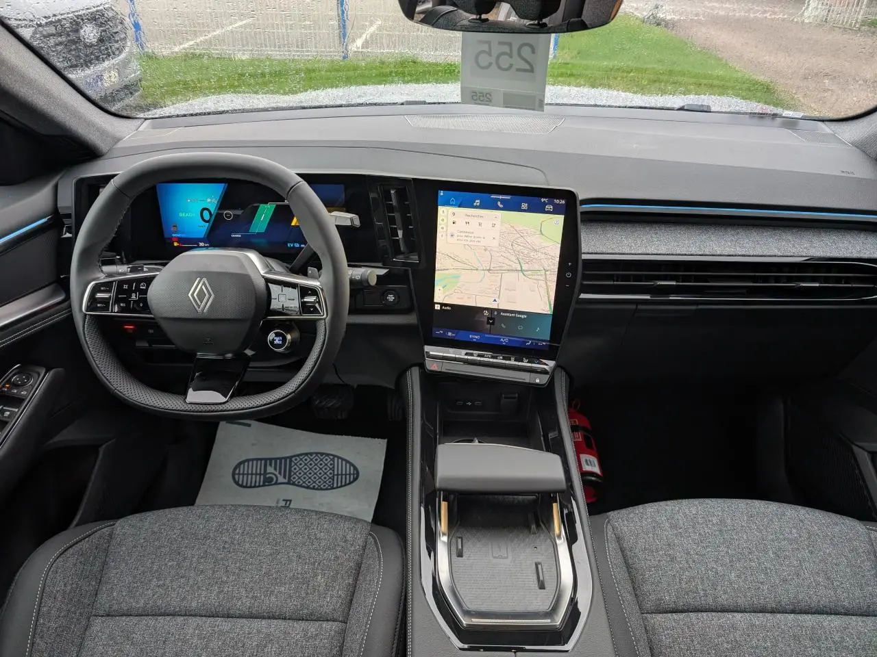 Vue intérieure avant du Renault Austral 2025 gris, avec tableau de bord numérique et écran tactile central vertical.