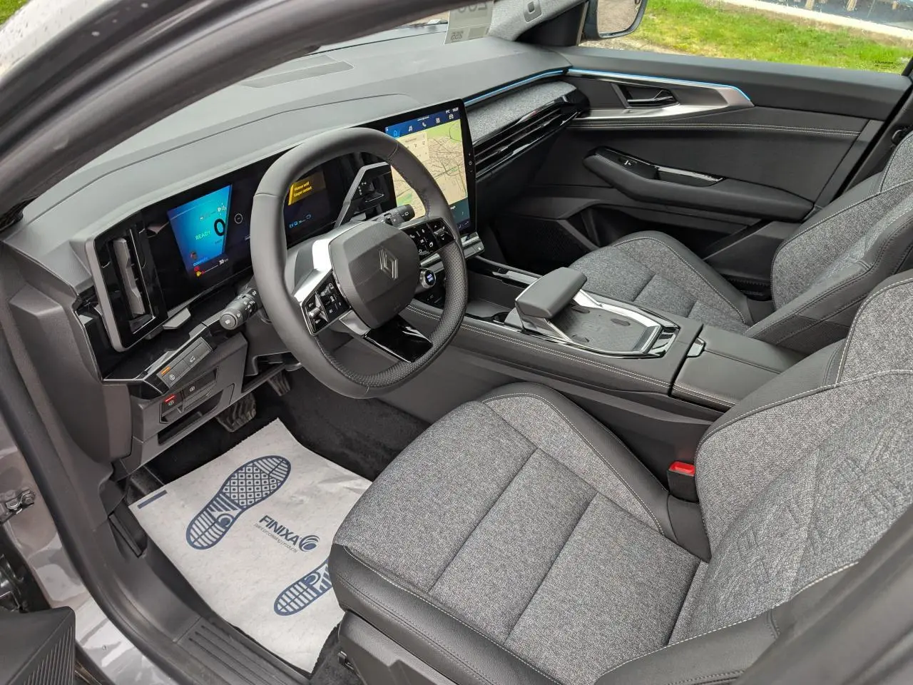 Vue intérieure côté conducteur du Renault Austral gris, avec tableau de bord numérique et sellerie tissu gris clair.