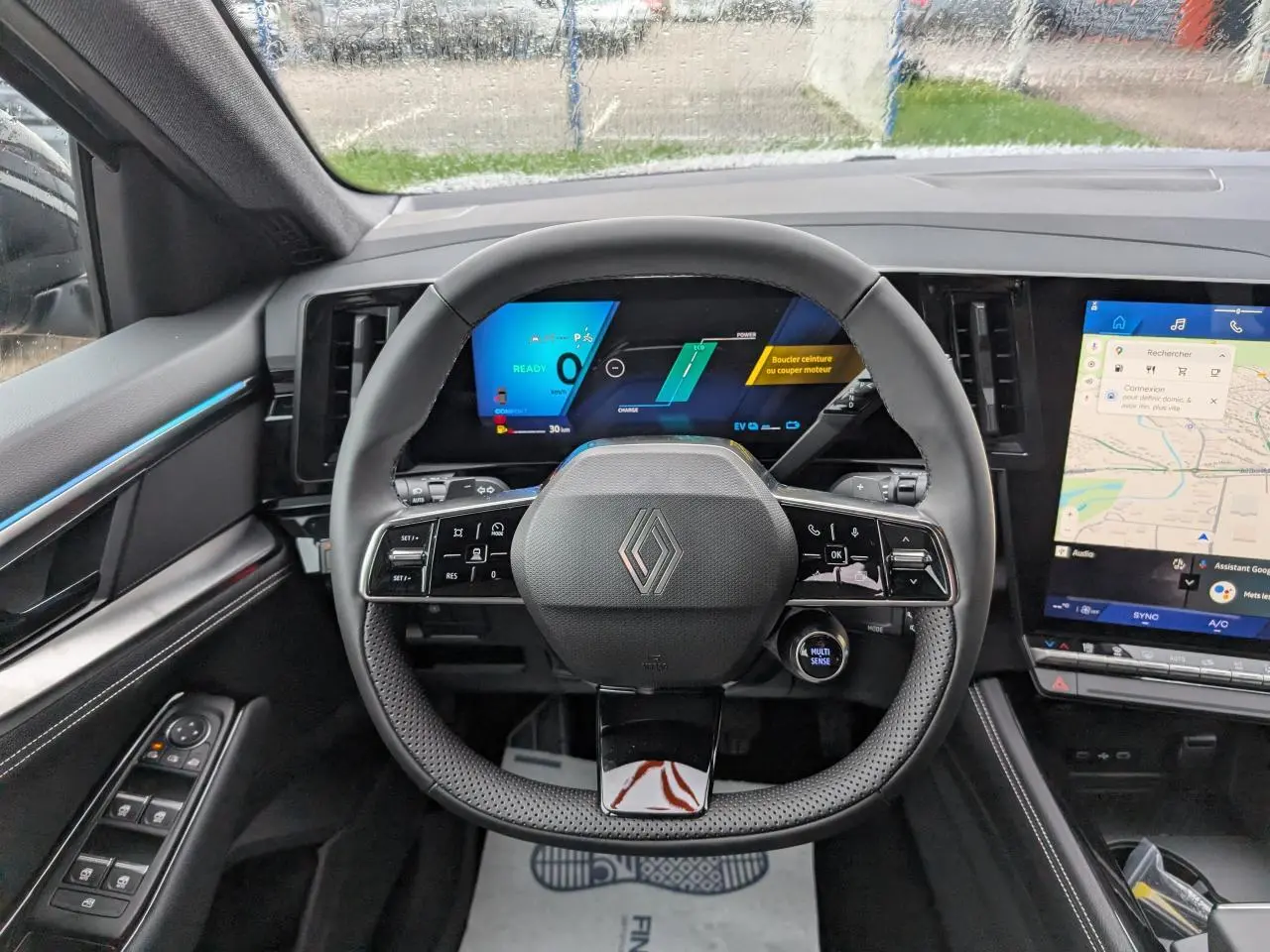 Vue intérieure centrée sur le volant noir du Renault Austral 2025 avec tableau de bord numérique et écran tactile latéral.