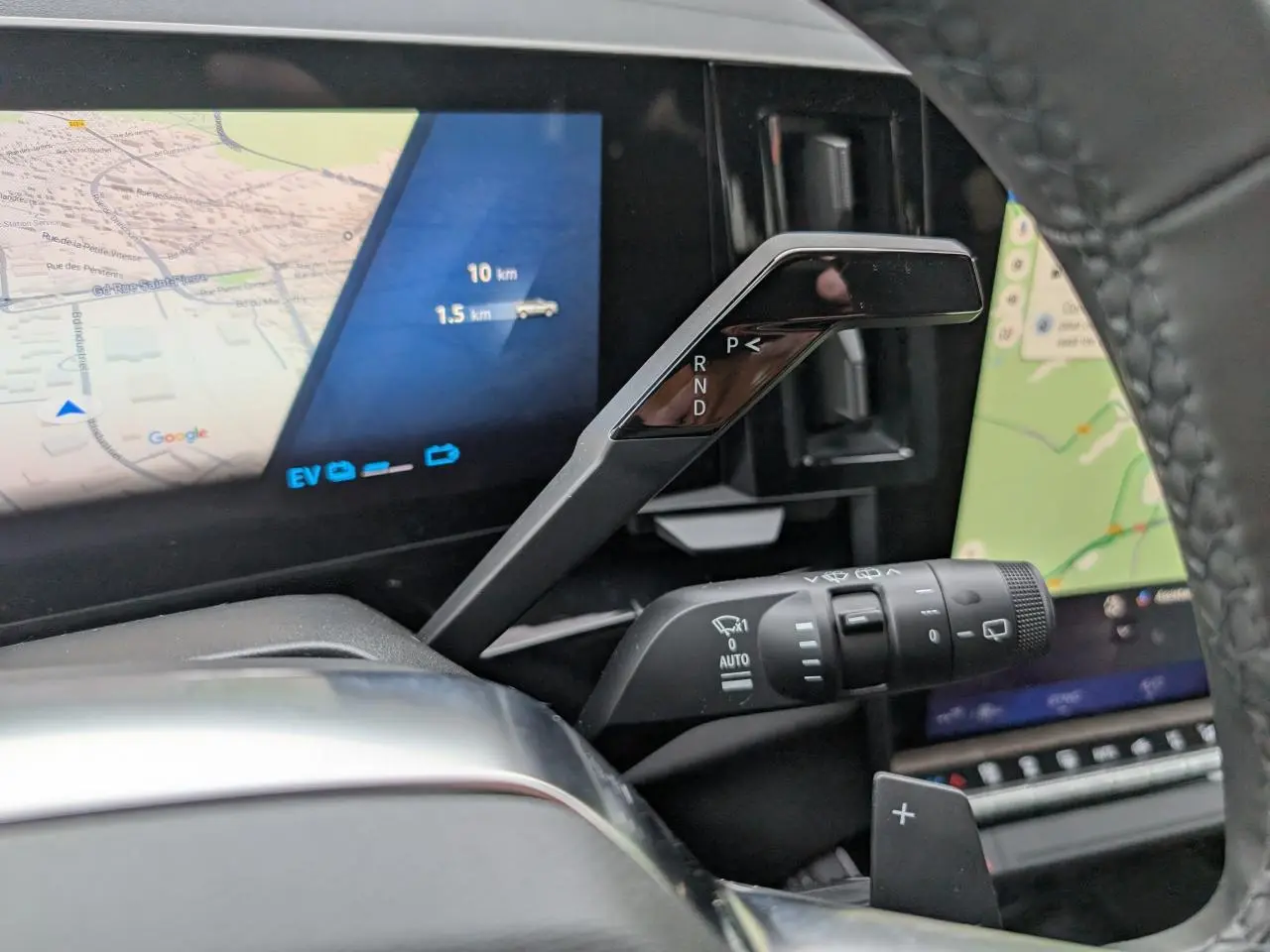 Gros plan intérieur sur la commande de boîte automatique et l’écran numérique du Renault Austral gris, affichant la navigation.