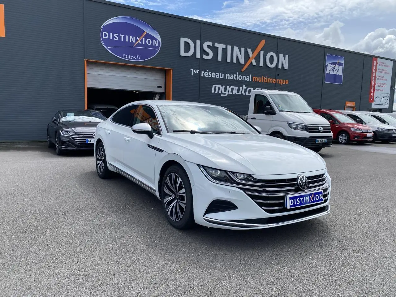 Volkswagen Arteon blanc pur en 3/4 avant droit, avec jantes alliage et calandre chromée visible.