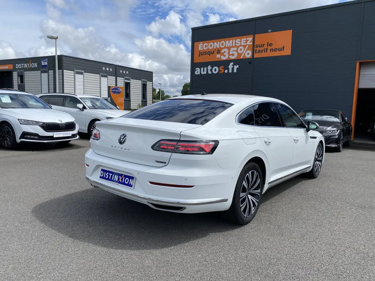 Volkswagen Arteon blanc pur vue 3/4 arrière droit avec jantes alliage et vitres teintées sur parking.