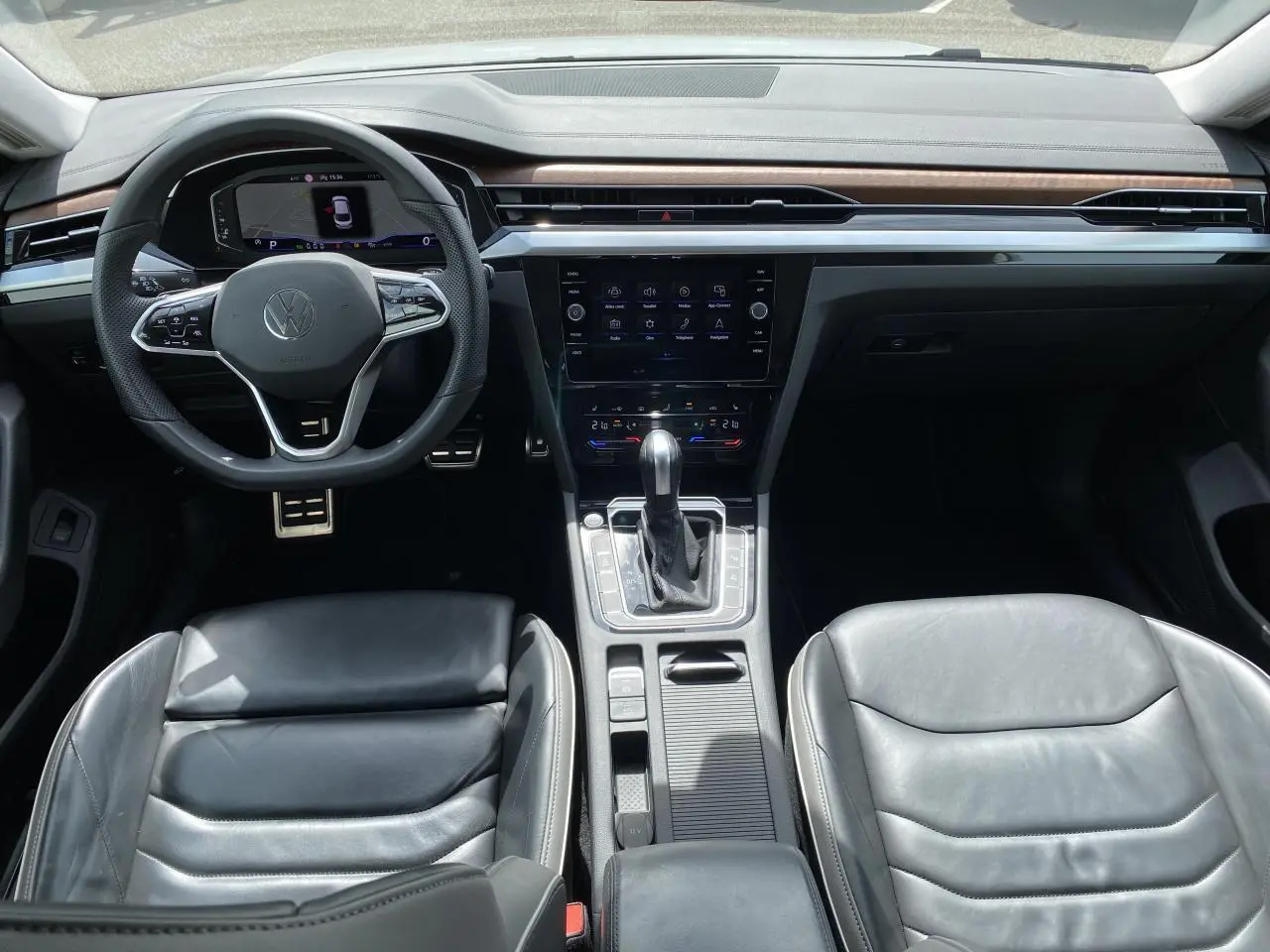 Vue intérieure avant du Volkswagen Arteon 2022, sellerie cuir noir, tableau de bord avec écran tactile et volant multifonction.