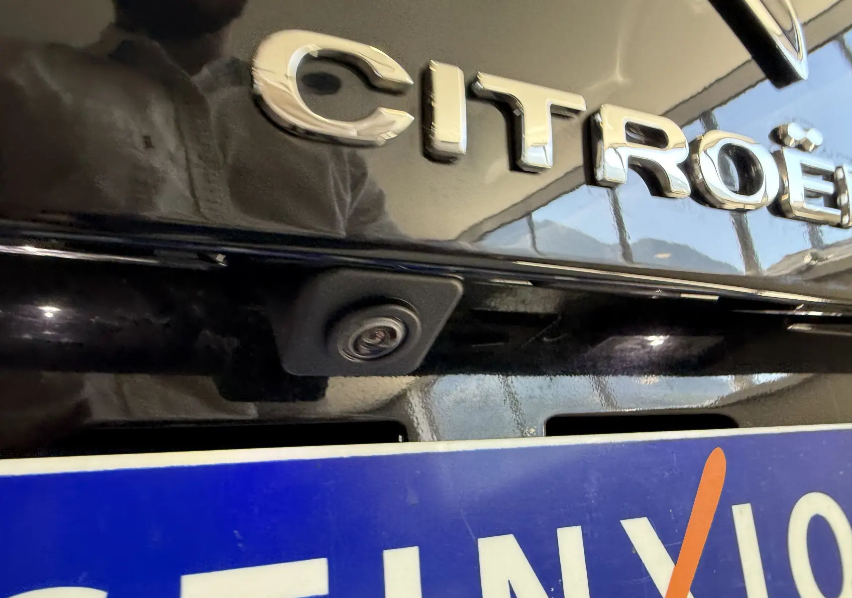 Gros plan sur la caméra de recul intégrée sous le logo Citroën sur la malle arrière noire du C5 Aircross.
