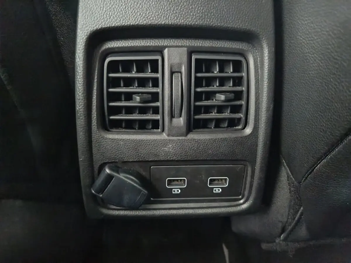 Vue rapprochée des prises USB et de la ventilation arrière noire dans l'habitacle du Renault Captur gris foncé.