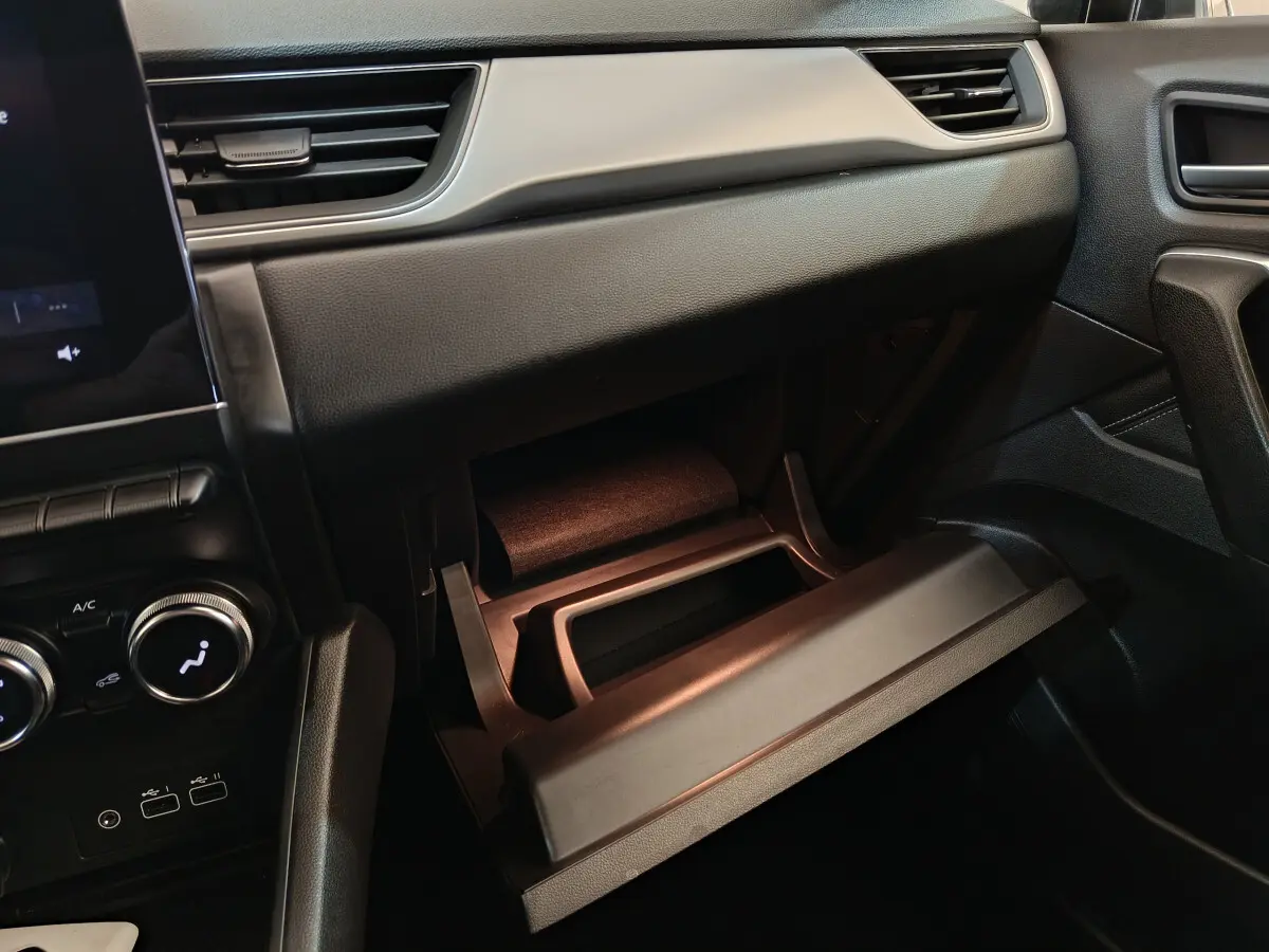 Intérieur du Renault Captur 2024 gris foncé, vue côté passager sur la boîte à gants ouverte et la console centrale.