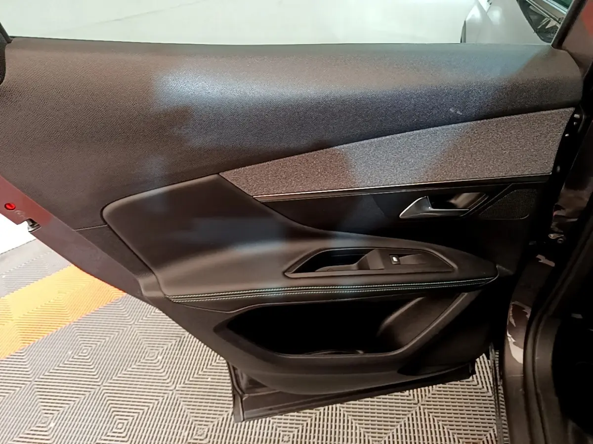 Vue intérieure sur la porte arrière droite du Peugeot 3008 gris foncé, avec garniture noire et détails en tissu gris.