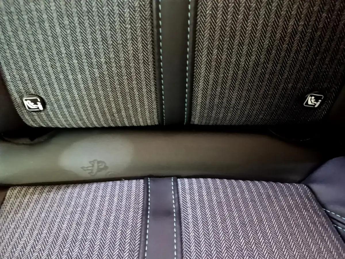 Détail de la banquette arrière gris foncé du Peugeot 3008 hybride, avec surpiqûres bleues et logos Isofix visibles.