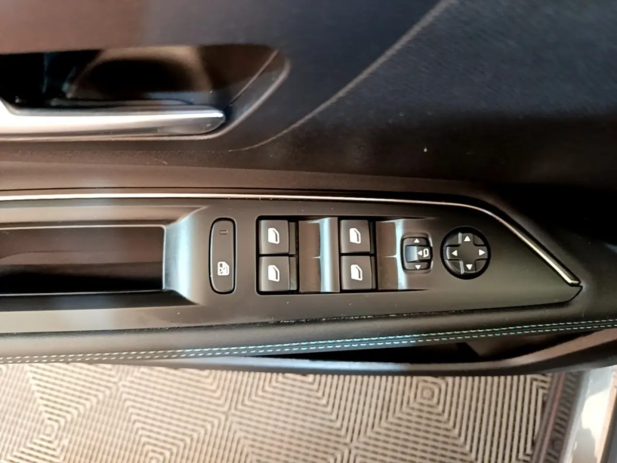 Commande des vitres et rétroviseurs côté conducteur sur porte intérieure noire avec surpiqûres bleues du Peugeot 3008 gris foncé.