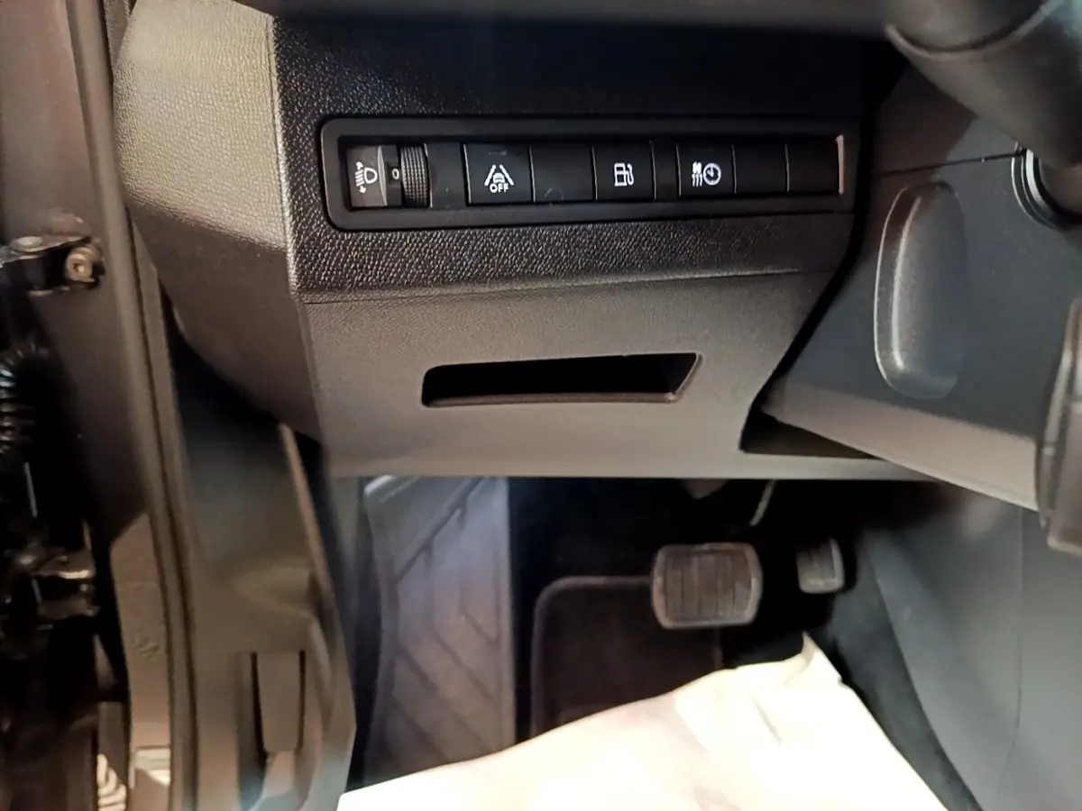 Vue intérieure côté conducteur du Peugeot 3008 gris foncé, montrant les commandes d'assistance et pédales au sol.