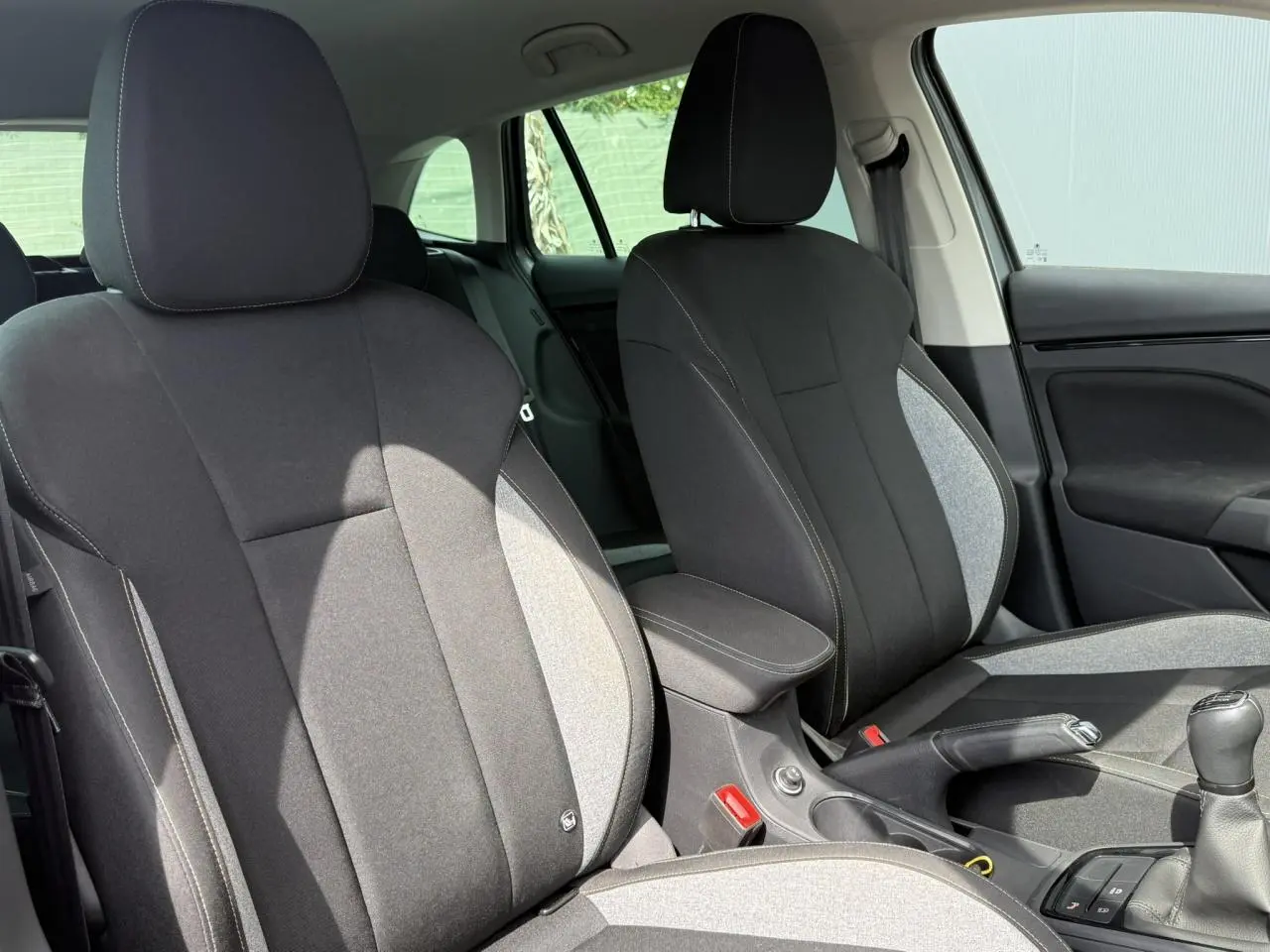 Vue intérieure des sièges avant tissu noir et gris avec accoudoir central et levier de vitesse manuel d'une Skoda Scala 2025.