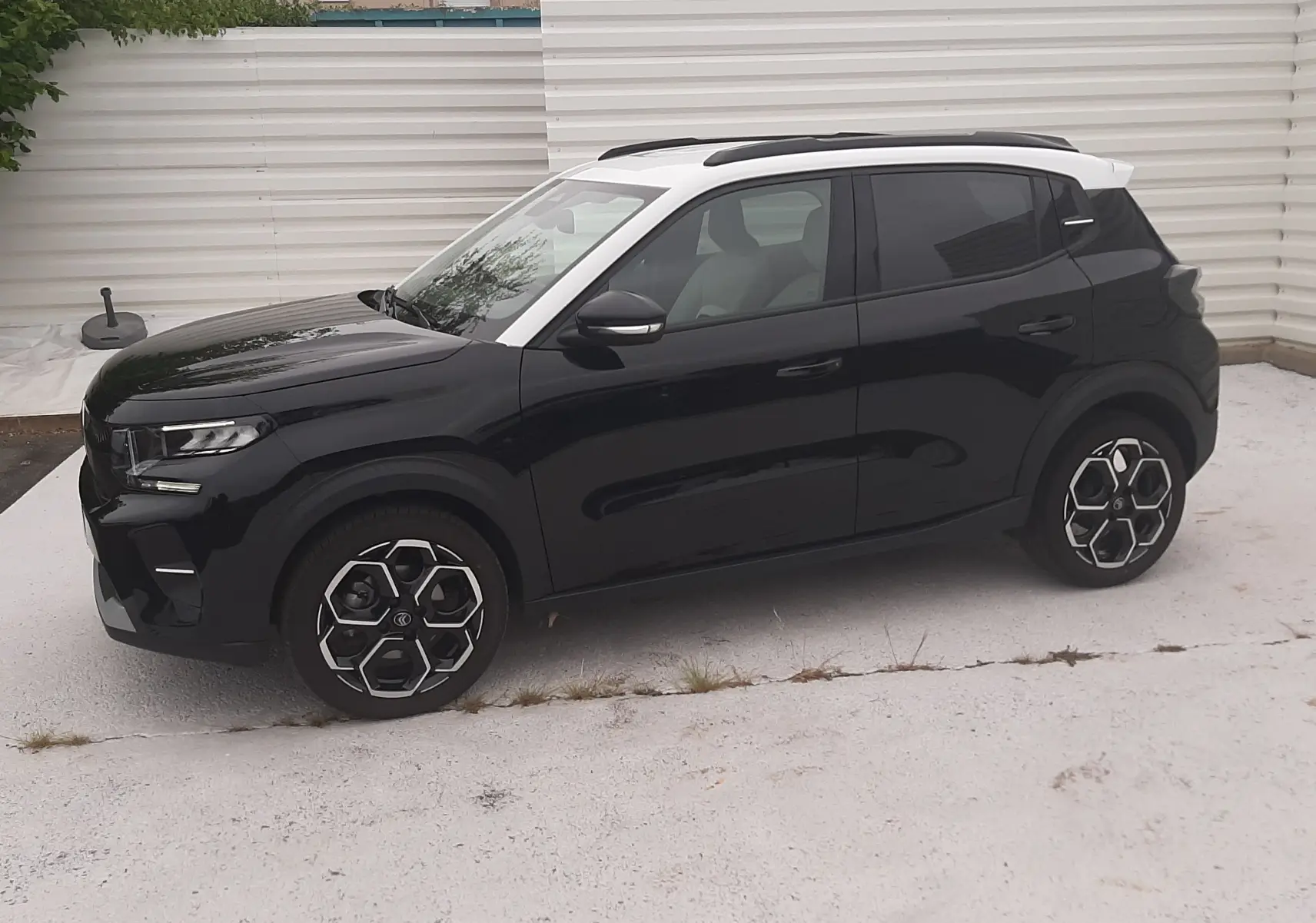 Vue de profil côté gauche d'une Citroën C3 2025 noir perla avec toit blanc et jantes bi-ton distinctives.