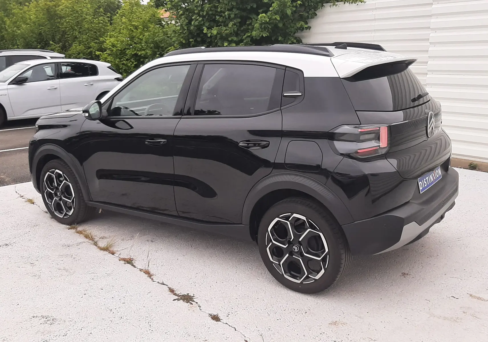 Vue 3/4 arrière droite d'une Citroën C3 2025 noir perla avec toit blanc et jantes biton distinctives.