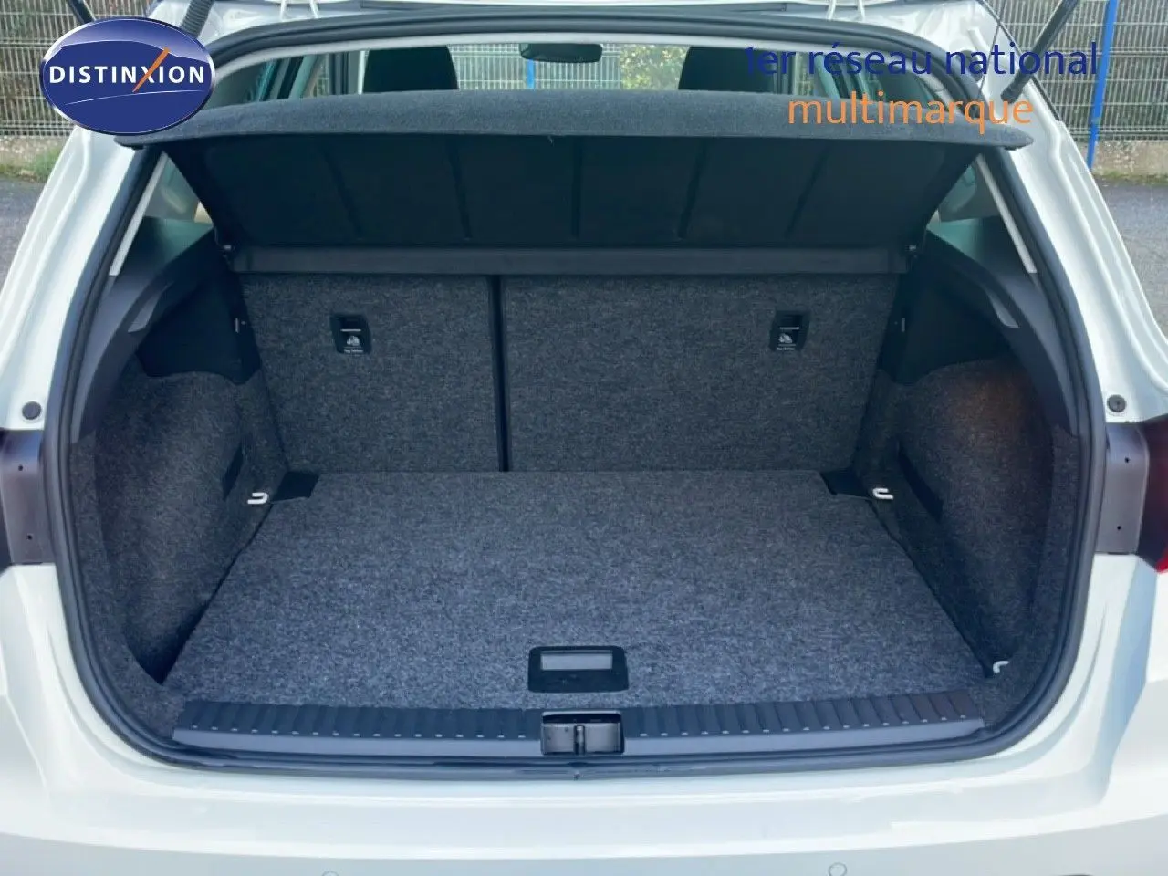 Coffre ouvert vu de l'arrière d'une SEAT Arona blanc avec toit gris, montrant l'espace de chargement et la moquette grise.