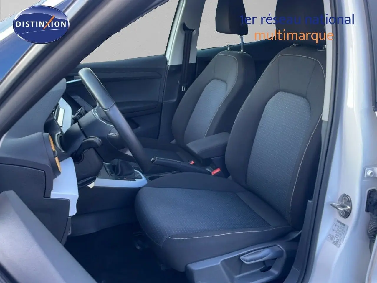 Vue intérieure côté conducteur du SEAT Arona blanc avec sièges tissu gris et volant multifonction cuir.