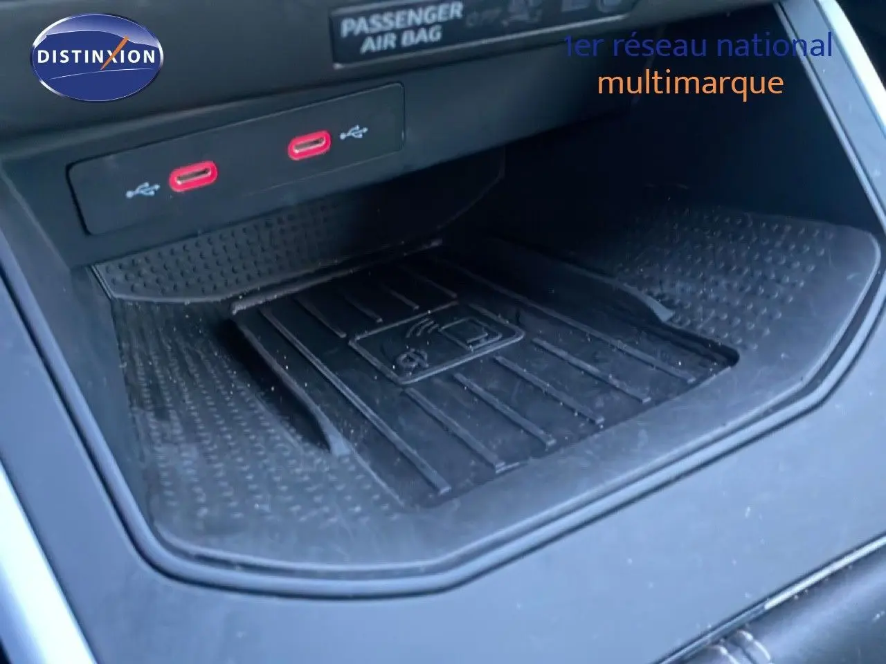 Gros plan sur la console centrale avec deux ports USB rouges et un espace de recharge sans fil dans un SEAT Arona blanc toit gris.